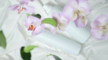 Kokulu orkide çiçekleri doğal çamaşır deterjanı jel ve kumaş yumuşatıcısı üzerine düşüyor.