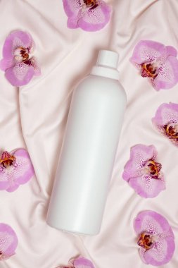Yatak çarşafları üzerinde orkide çiçekleri arasında ekolojik çamaşır deterjanı