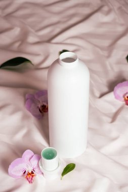 Yatak çarşaflarındaki orkide çiçeklerinin arasında ekolojik deterjan.