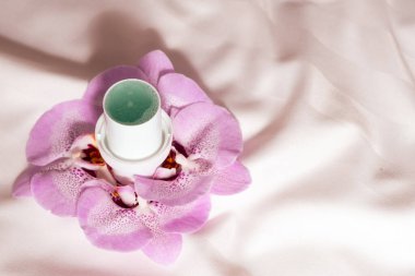 Arka planda saten kumaş çiçekli doğal sıvı deterjan.