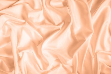 Dalgalar ve buruşuk doğal saten kumaş desenleri. 2024 Peach Fuzz Yılı Rengi.