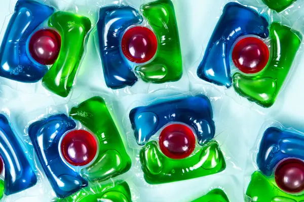 Mavi arkaplandaki çamaşır kapsülleri yakın plan.