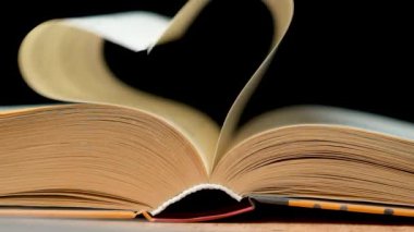 Kitap sayfaları siyah bir arkaplanda kalp şeklinde katlanmış..