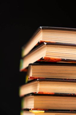 Siyah arka planda bir yığın eski kitap. Bilgelik ve bilgi, okuma aşkı.