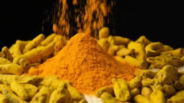 Tahta tabağa zerdeçal tozu serpiştirilmiş toz ve kuru zerdeçal kökü, yavaş çekim