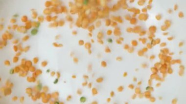 Çiğ bezelye Groats bir tabak makro yavaş çekim üst görünüm içine dökülüyor.