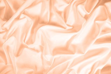 Dalgalar ve buruşuk doğal saten kumaş desenleri. 2024 Peach Fuzz Yılı Rengi.