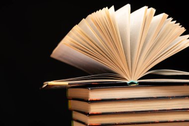 Siyah arkaplan üzerine kitap yığını, açık kitap