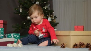 Bir yaşından küçük bir çocuk çocuklar için güvenli Noel oyuncaklarıyla oynuyor..