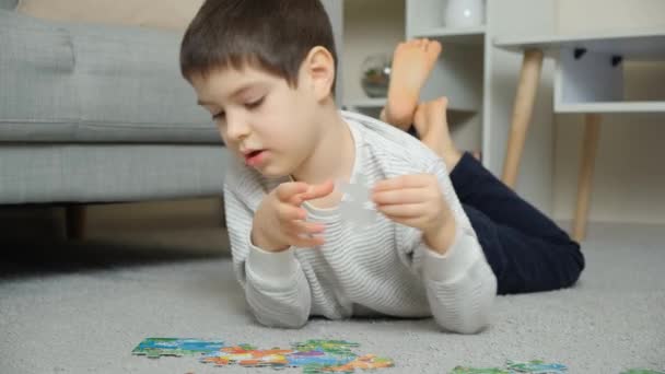 一个孩子躺在地毯上拼凑拼图 学龄前儿童和小学生的教育课 — 图库视频影像
