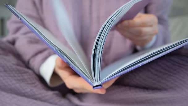 一个穿紫色睡衣的女人翻阅一本书 — 图库视频影像