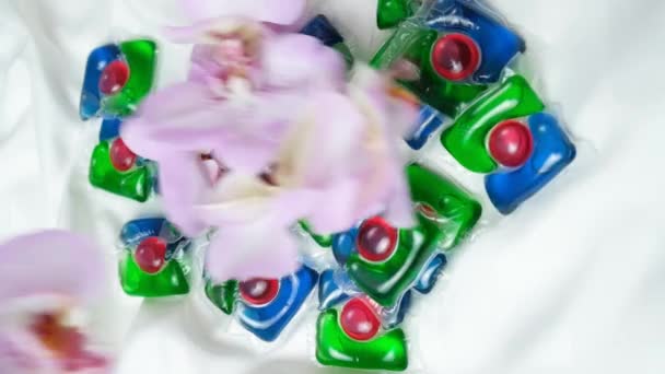 在缎子织物上的兰花之间的洗衣胶囊 垂直慢动作 — 图库视频影像