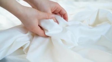Kadın çizgili saten kumaşa eliyle dokunuyor, nazikçe okşuyor, yakından..