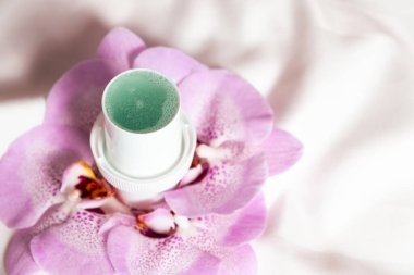 Arka planda saten kumaş çiçekli doğal sıvı deterjan.