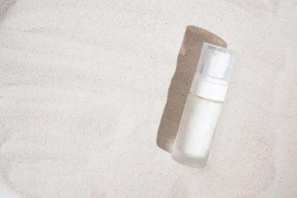 Natural eco cosmetics cream in white bottle on the sand, place for text.