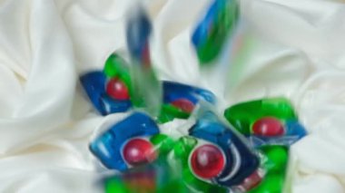 Kapsüllerdeki sıvı çamaşır deterjanı yavaşça kumaşın üzerine düşüyor.