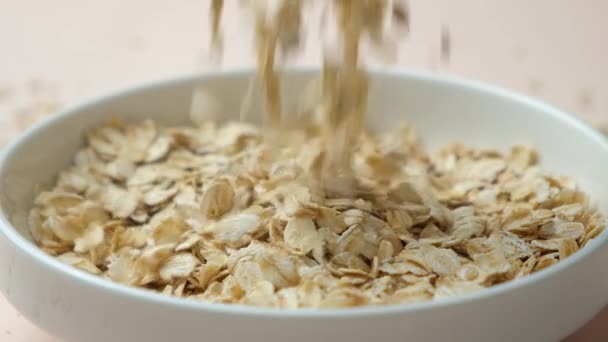 Copos Avena Secos Vertiendo Plato Sobre Fondo Rosa Cámara Lenta — Vídeos de Stock