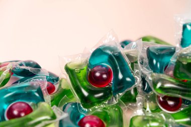 Bej arka planda çamaşır kapsülleri yakın plan.