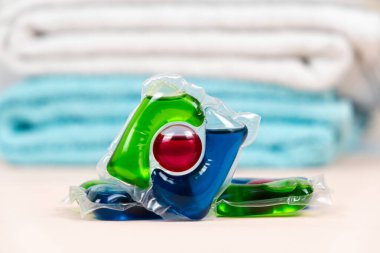 Bej arkaplandaki çamaşır kapsülleri yumuşak havlularla.