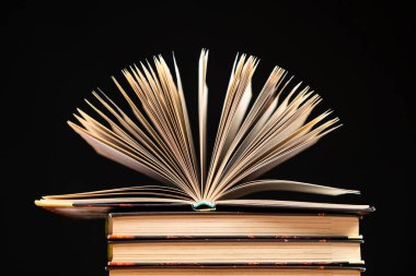 Siyah arkaplan üzerine kitap yığını, açık kitap