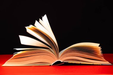 Kalın bir kitabın sayfaları kırmızı ve siyah arkaplanlarla çevrilidir.