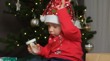 Komik küçük çocuk Noel Baba 'nın şapkasını kafasından çıkarıyor. Noel Çocukları.