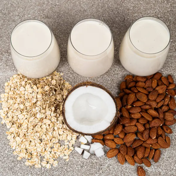 Types of plant-based milk in glasses. Oat, coconut and almond milk