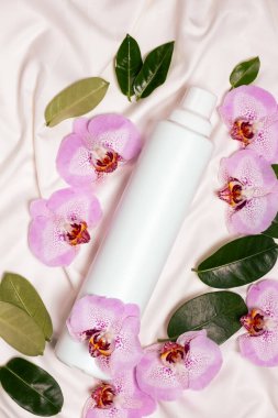 Yatak çarşafları üzerinde orkide çiçekleri arasında ekolojik çamaşır deterjanı