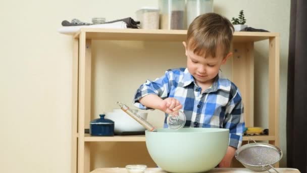 一个两岁的男孩准备面团 把配料倒入碗里 厨房里的孩子 — 图库视频影像