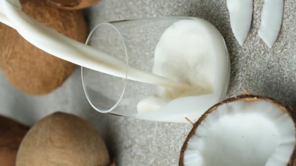 ココナッツミルクは ココナッツの中のガラスに注ぎ 垂直スローモーション — ストック動画