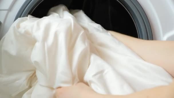 洗濯機にベッドリネンを置いてドアを閉める女性 — ストック動画