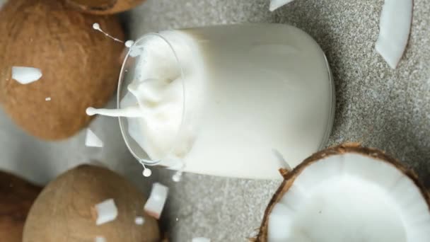 ココナッツスライス ココナッツミルクのガラスに落ちる 垂直遅い動き — ストック動画