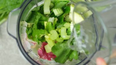 Mikserde yeşil smoothie yapmak, sebzelere su eklemek, üst manzara.