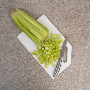 Taş beyaz tahta üzerinde doğranmış yeşil kereviz sapları