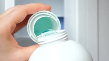 Deterjan dolu bir çamaşır makinesinin arka kapağına sıvı jel dökülüyor..