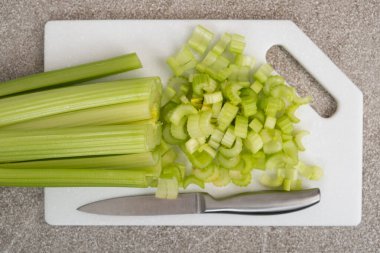 Taş beyaz tahta üzerinde doğranmış yeşil kereviz sapları