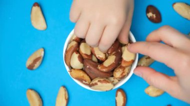 Yetişkin ve çocuğun elleri Brezilya fıstığını tabaktan alıyor.