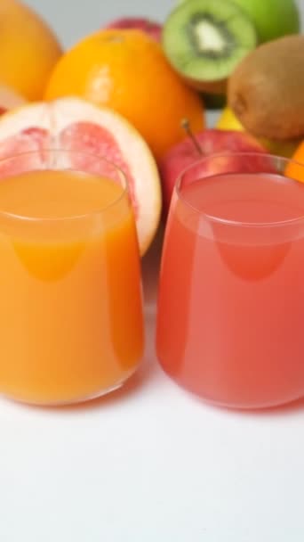 新鮮なフルーツ 垂直射撃の間のメガネの多彩な果物およびグレープフルーツ ジュース — ストック動画