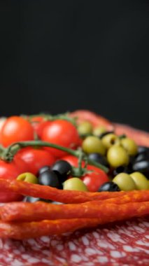 Güzel servis edilmiş sosis dilimlenmiş et lezzetleri siyah arka planda dönüyor.