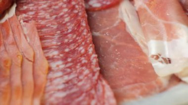 Pirzola, salam, jambon ve yakın plan dönen sosisler.