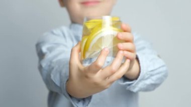 Elinde bir bardak limon suyu tutan mutlu altı yaşındaki çocuk.