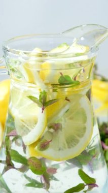 Limonlu ev yapımı limonata ve cam sürahide naneli, dikey ağır çekimde.