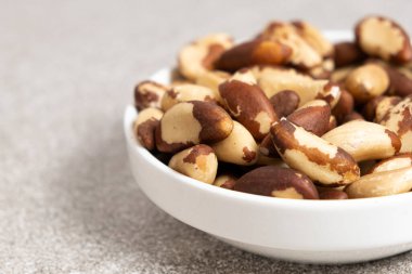 Brazil nuts in plate on grey background, copy space for text.