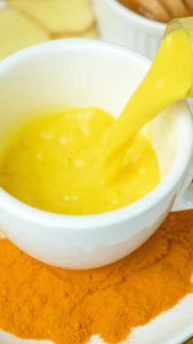 Altın süt bardağa doluyor, ağır çekimde. Zerdeçal ile geleneksel Ayurvedic içecek