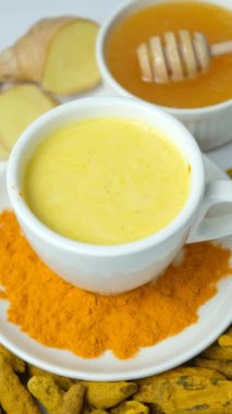 Geleneksel Ayurvedic zerdeçal, karabiber ve zencefilli altın süt içer. Dikey ağır çekim.