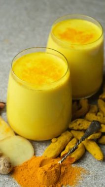 Altın süt, gri arka planda iki bardak zerdeçal içeren geleneksel bir Ayurvedik içeceği..
