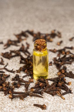 Kurumuş karanfillerin arasında cam şişedeki doğal karanfil yağı..