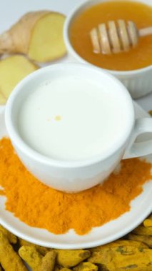 Zerdeçal sütü yapıyorum. Zerdeçal tozu bir bardak sıcak süte dökülüyor, dikey ağır çekimde..