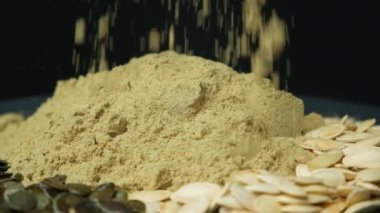 Yer kabağı tohumları, un siyah bir zemine dökülüyor, yavaş çekim.