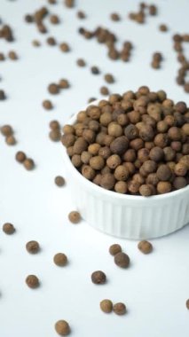 Siyah karabiberleri yakın plan beyaz arka planda bir tabakta..